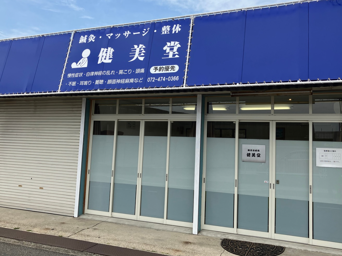 斜めから見た青い看板が目印の健美堂の外観