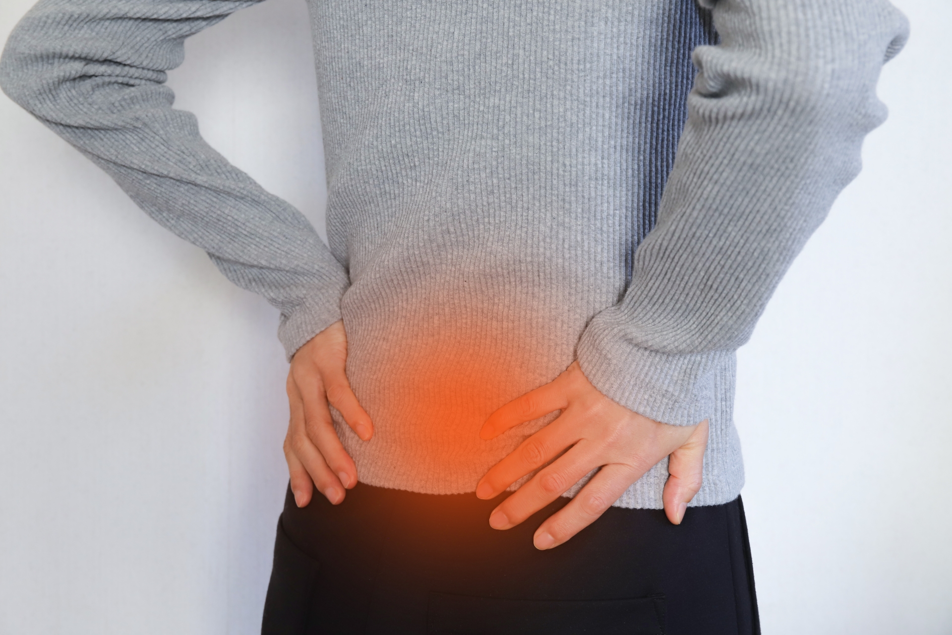 腰を抑えて痛みを感じている男性。腰痛・坐骨神経のイメージ