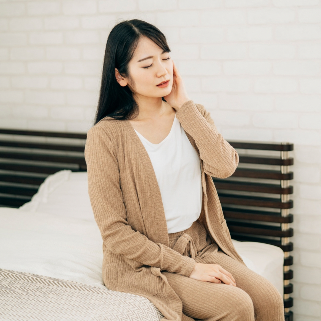 首をおさえてつらそうにする女性。寝違えの鍼灸