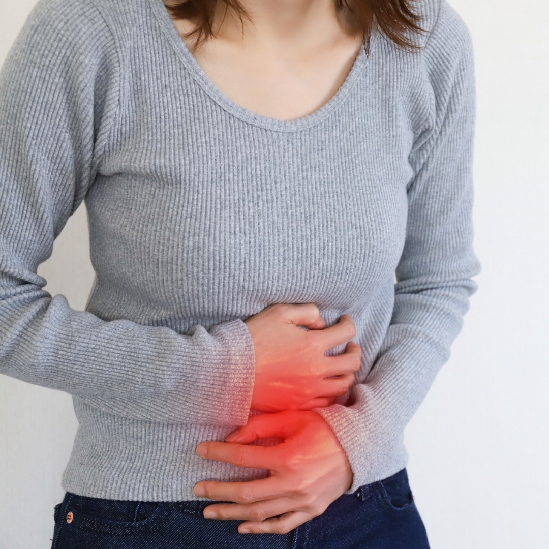 胃もたれでお腹を押さえる女性