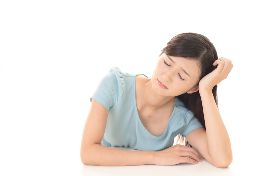 机に肘をつき、頬に手を添えて目を閉じる女性 — 慢性的な疲れ・だるさのイメージ|貝塚市の鍼灸治療院 健美堂